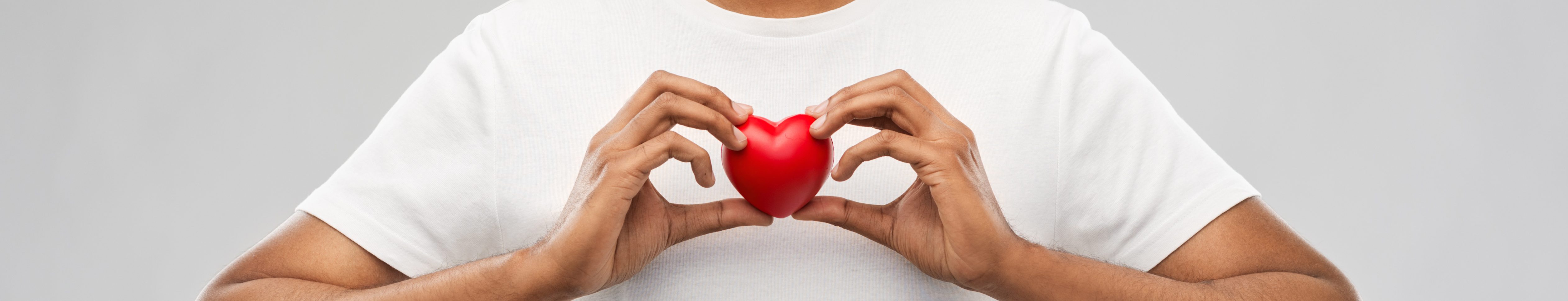 man holding red heart over grey background